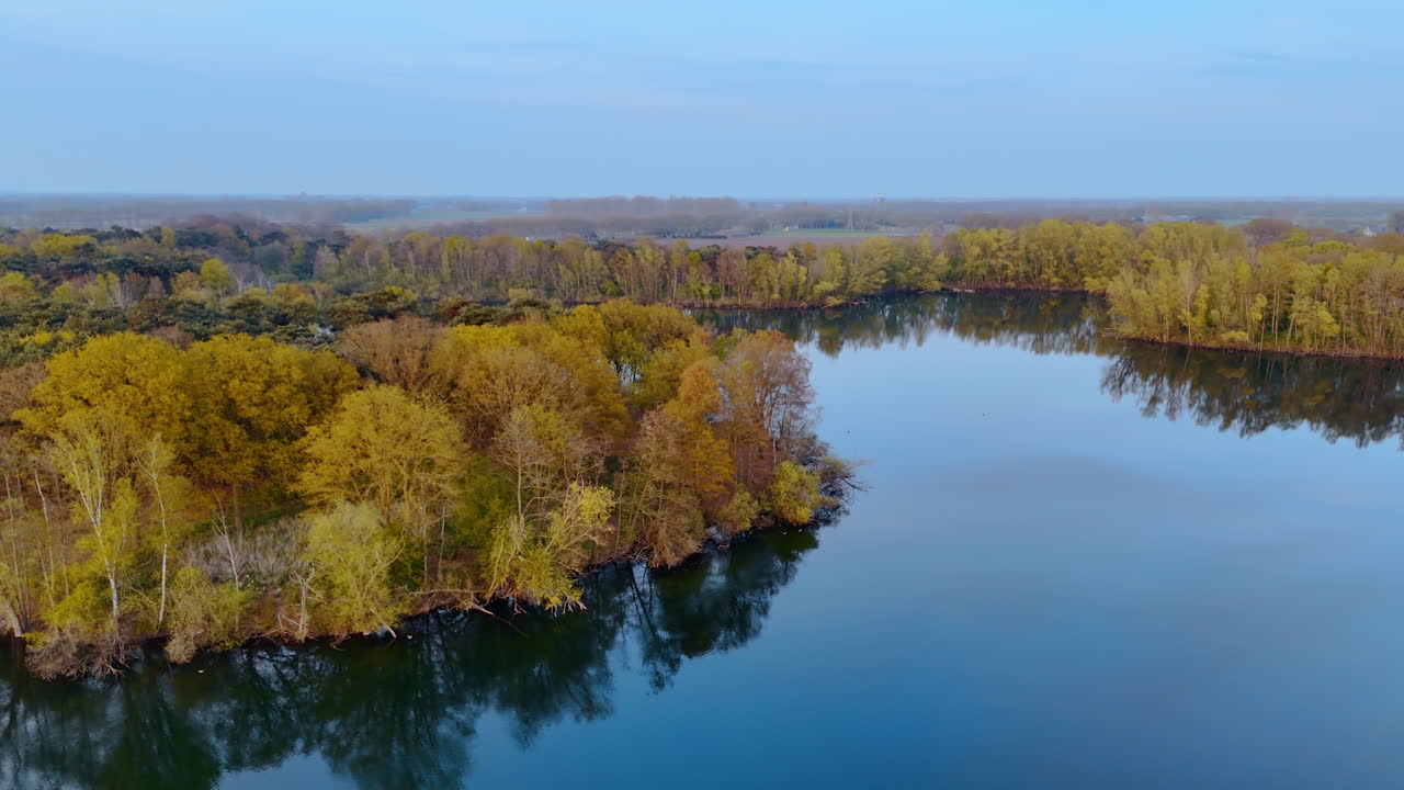 Beautiful aerial view of Dutch landscape. Vibrant hues of autumn foliage reflect in quiet waters of a lake in the Netherlands during a peaceful morning