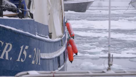 video en cámara lenta de ofertas naranjas en un barco en tormenta de nieve amarrado en un puerto congelado en groenlandia