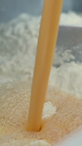 pouring egg into flour mixture for baking