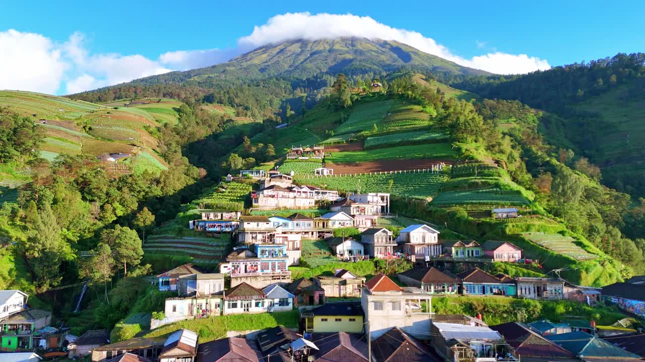 Beautiful drone footage showcasing a rural mountain community surrounded by fertile farmland and scenic hills under blue sky. Nepal Van Java Village, Mount Sumbing, Indonesia