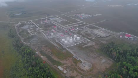 the drone rises over the oil and gas field in the swamps of siberia. oil tanks and industrial buildings are covered with a gray fog. rejection of russian oil and gas. fuel crisis in the world