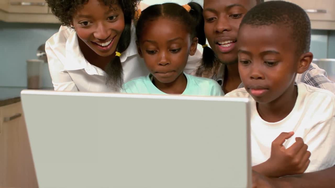 Famiglia nera felice che usa il laptop in cucina