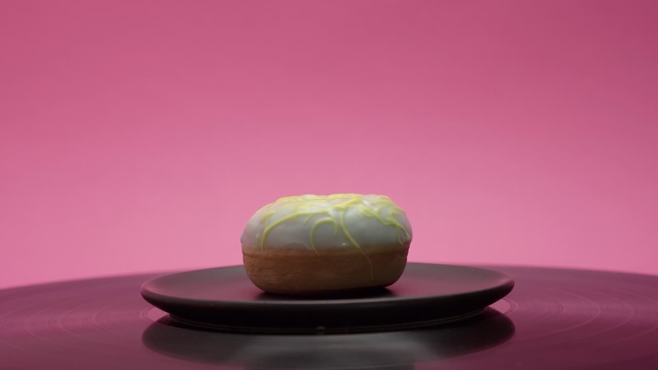 Sweet little donut with yellow and blue sugar toppings on a pink background