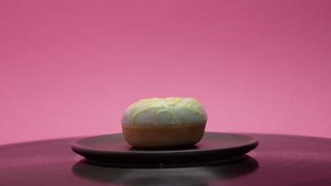 sweet little donut with yellow and blue sugar toppings on a pink background