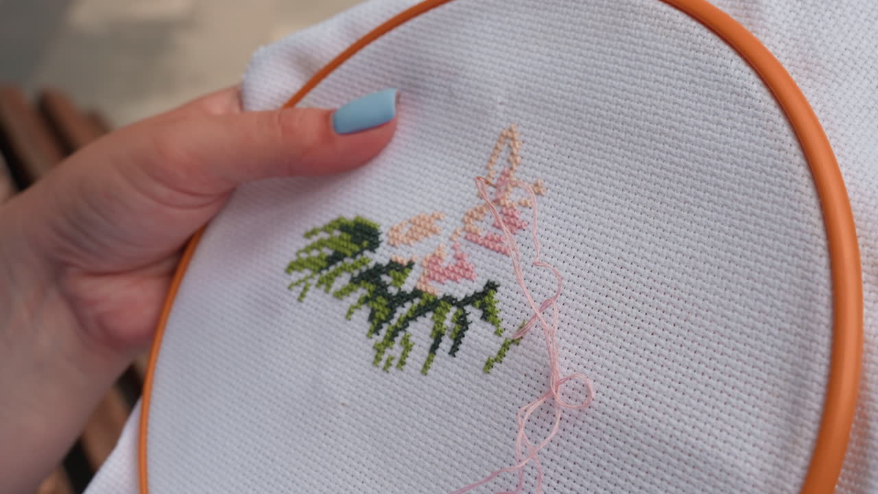 Close up of skilled person embroidering fabric with delicate tree like floral design, needle creating colorful stitches on white cloth, showing patience, precision, and creativity