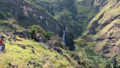 people and the local community walking to the huge dokomali waterfall in the remote, rugged mountains of ainaro district in rural countryside of timor leste, southeast asia