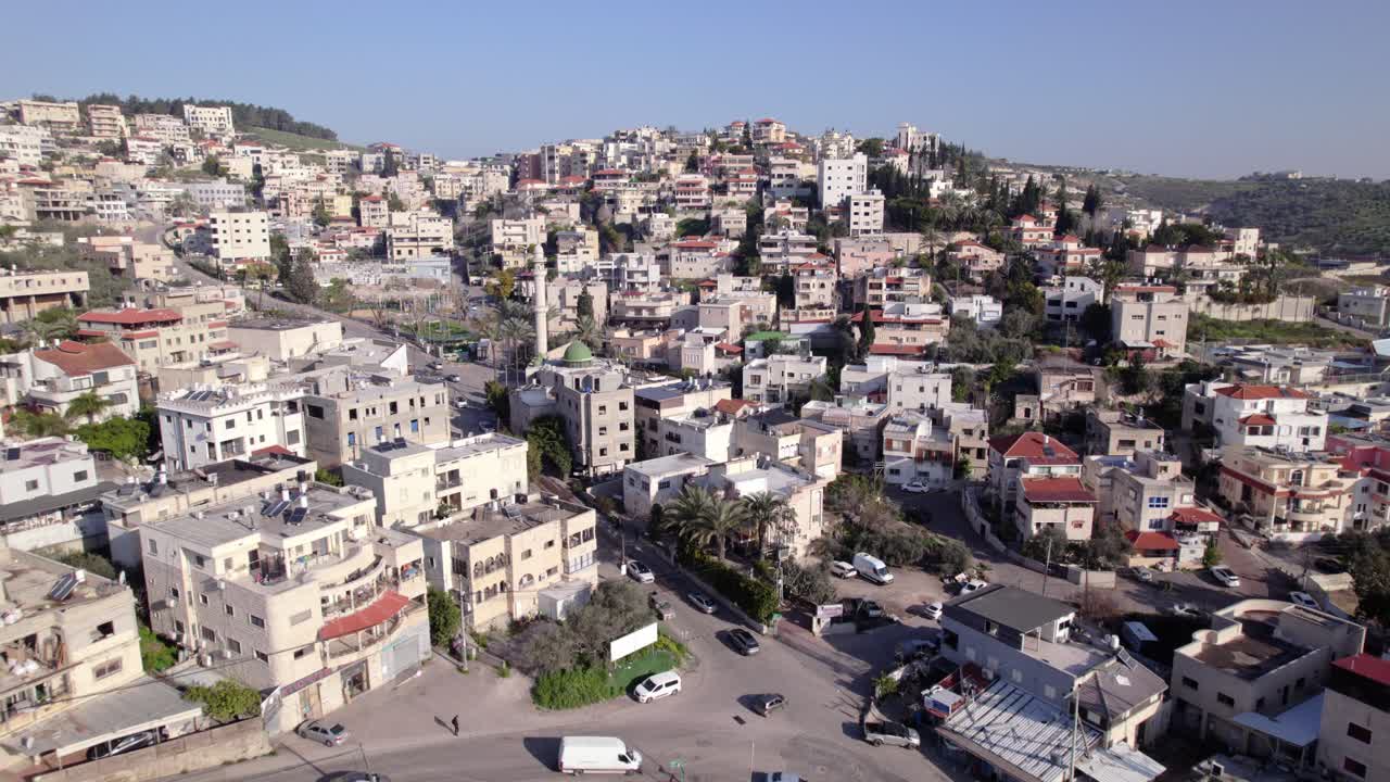 Ripresa aerea dall'alto con drone di Umm al-Fahm, una delle principali città arabe nella regione di Wadi Ara, nel nord di Israele, che mostra densi quartieri residenziali in collina, incroci stradali urbani, minareto di moschea, comunic