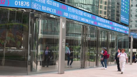 at exchange square, home of the hong kong stock exchange (hkex), a moving screen displays negative stock ticker symbols as pedestrians walk through the bustling financial district of hong kong.