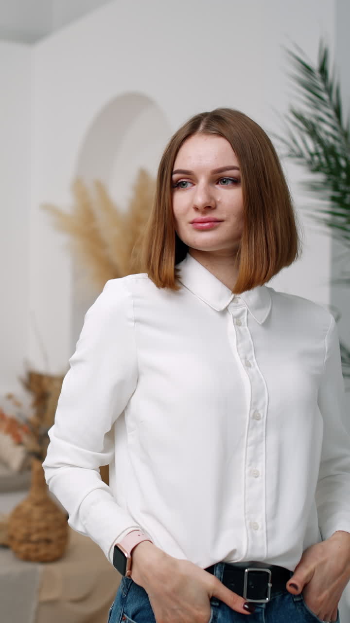 Woman in white shirt and jeans posing in the room in front of camera