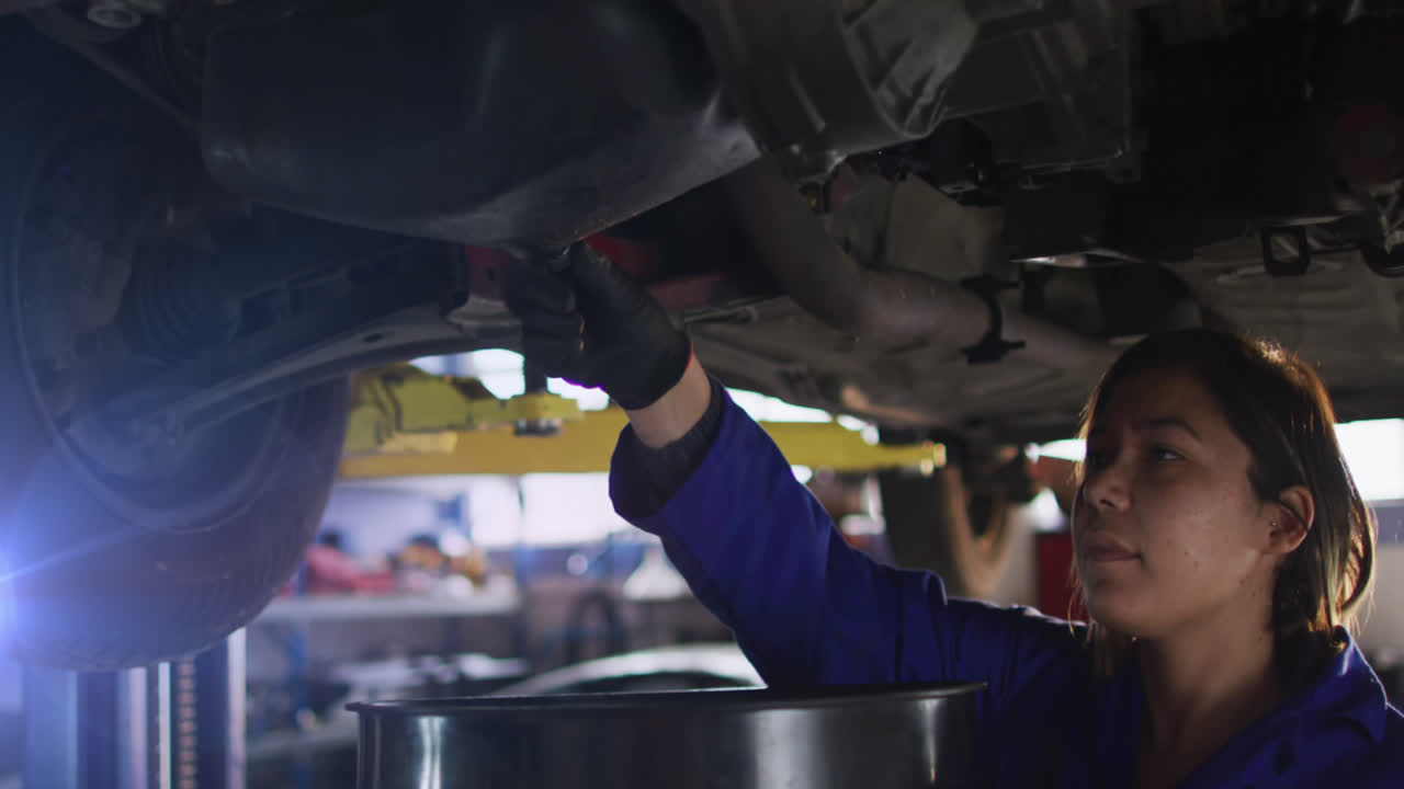 중성인 여성 아시아 기계공이 차고에서 자동차 엔진 오일을 배수하는 애니메이션