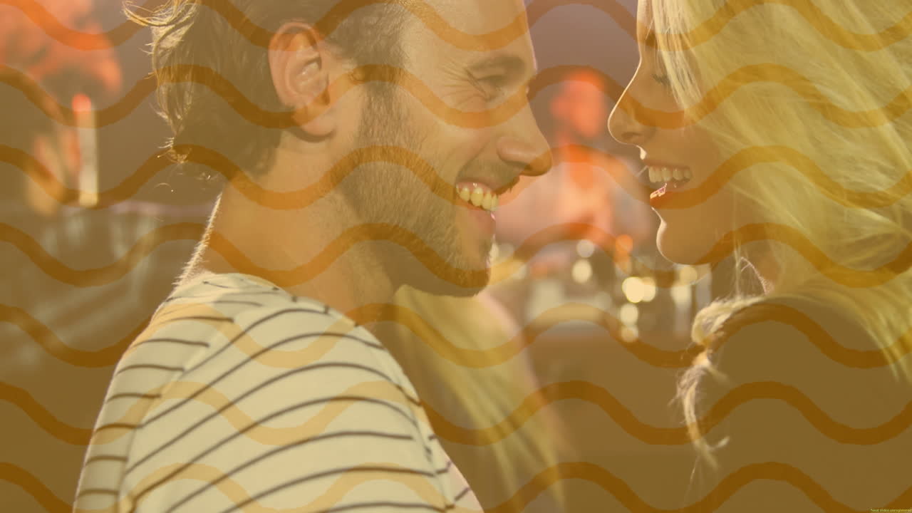 Couple sharing smiles in lounge, showing wavy orange stripes and bokeh lights for marketing