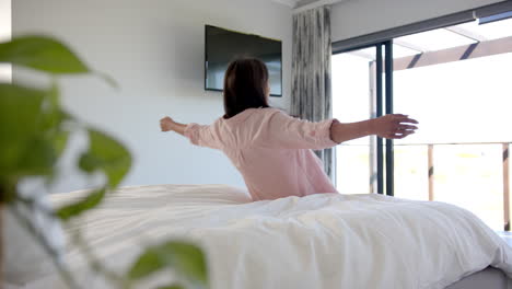 Relaxing on bed, woman watching TV in modern home bedroom