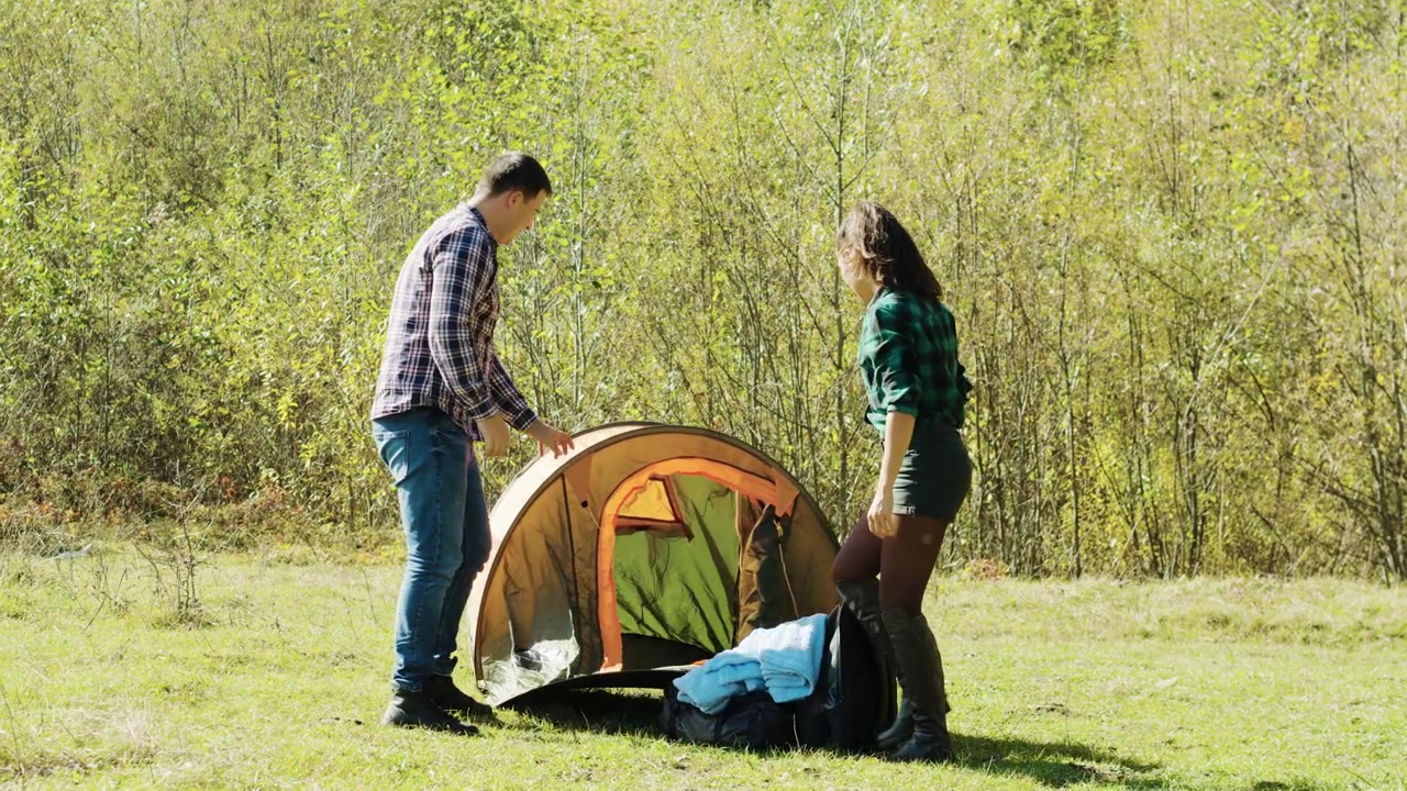 Camping partners assemble a tent at a mountain campsite