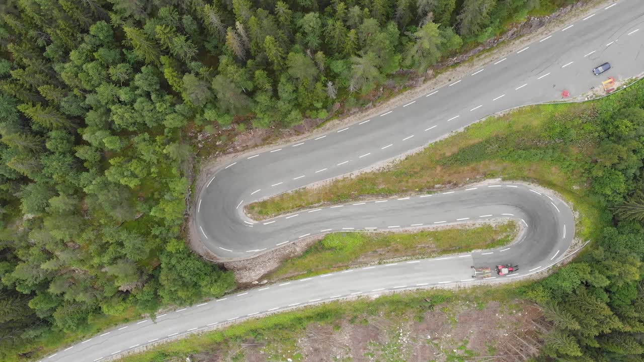 tractor conduciendo por el camino de bosque de montaña sinuoso horquillas, vista aérea de arriba hacia abajo