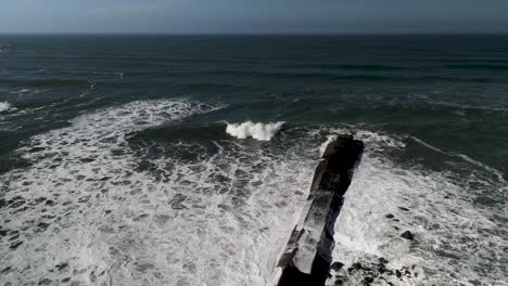 Passing-over-the-Coquille-River-Jetty-and-across-emerald-green-waters-of-the-Pacific-Ocean,-aerial