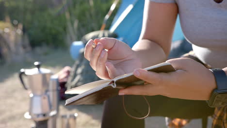 writing in journal, woman sitting outdoors during mountain hike with camping gear