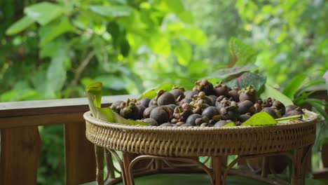 a bowl adorned with banana leaves presents a fresh assortment of vibrant mangosteen, a feast for the eyes and palate