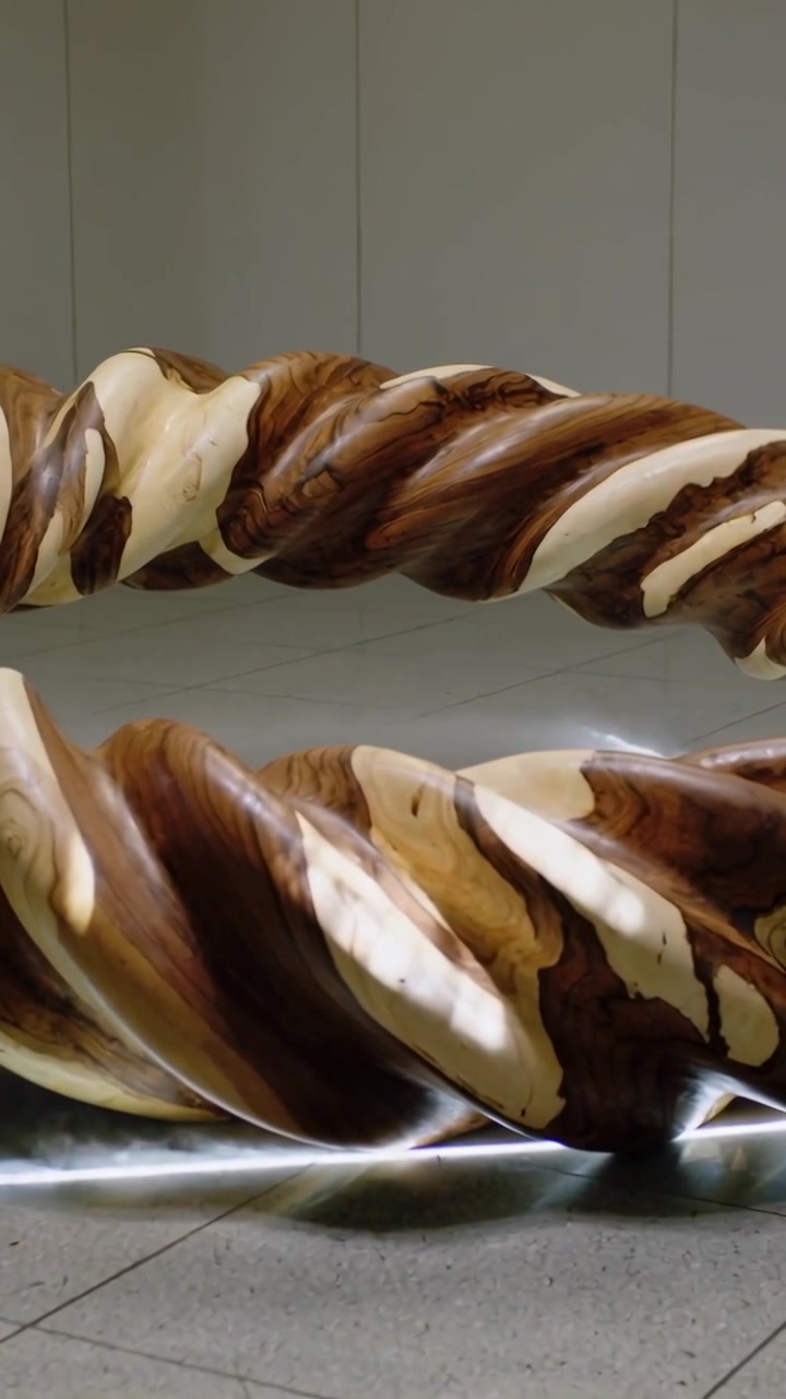 Video verticale: Telecamera che si posiziona panoramando su spirali di legno contorte in una galleria, mostrando le venature con nebbia LED.