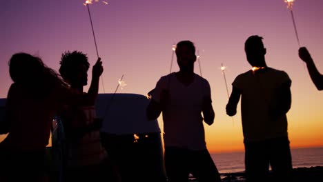 young adult friends having fun on the beach at night with sparklers 4k