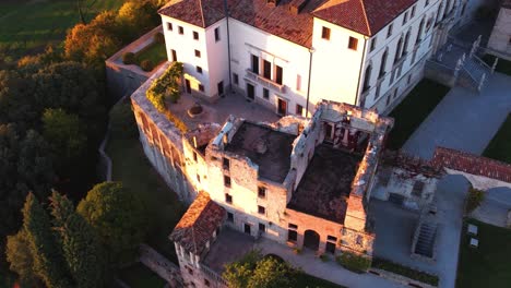 aerial view over a medieval castle on top of a hill, surrounded by prosecco vineyards, in italy, at sunrise