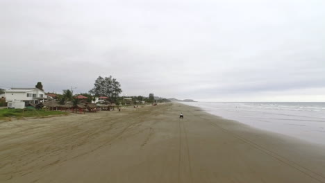 conduciendo un atv en la playa de arena de la curia en un día nublado en santa elena, ecuador