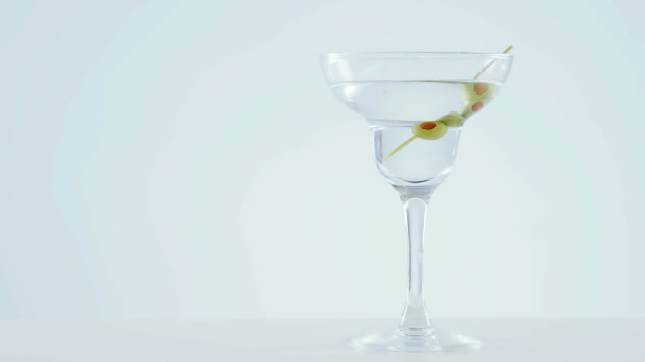 Design a motivo chevron su olive in un bicchiere da cocktail su sfondo grigio.