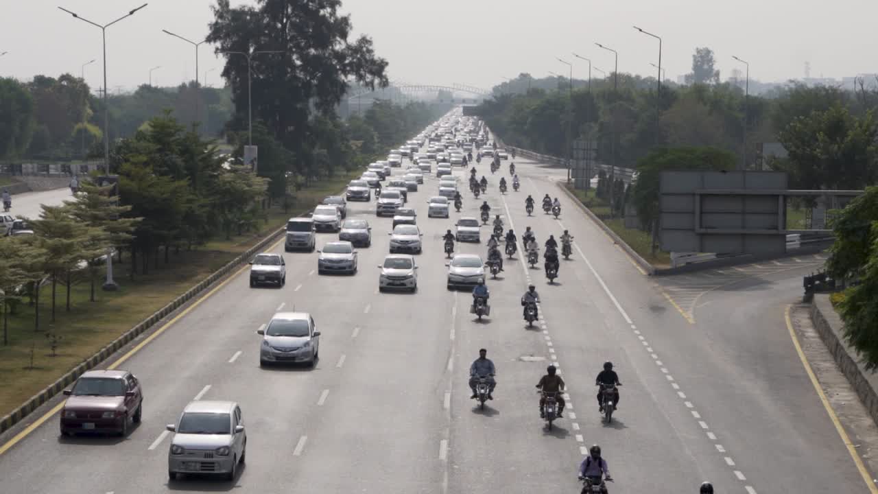 A captivating aerial shot of a busy urban street shows a variety of vehicles from the perspective of a bridge above.