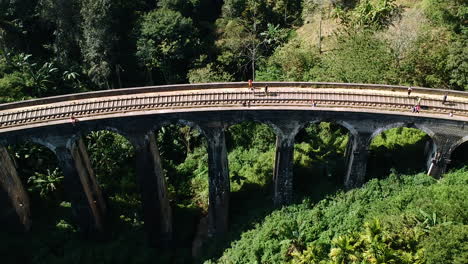 aerial of famous nine arch bridge in ella, sri lanka with blue train