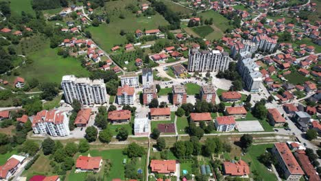 La-Vista-Aérea-De-Una-Zona-Suburbana-Con-Edificios-Residenciales-Altos-Y-Bajos,-Espacios-Verdes,-Carreteras-E-Instalaciones-Comunitarias