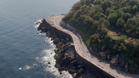 beautiful coastal road on rocky cliffside, tropical coastline, aerial drone view