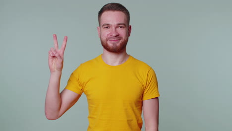 handsome stylish smiling man showing victory sign, hoping for success and win, doing peace gesture