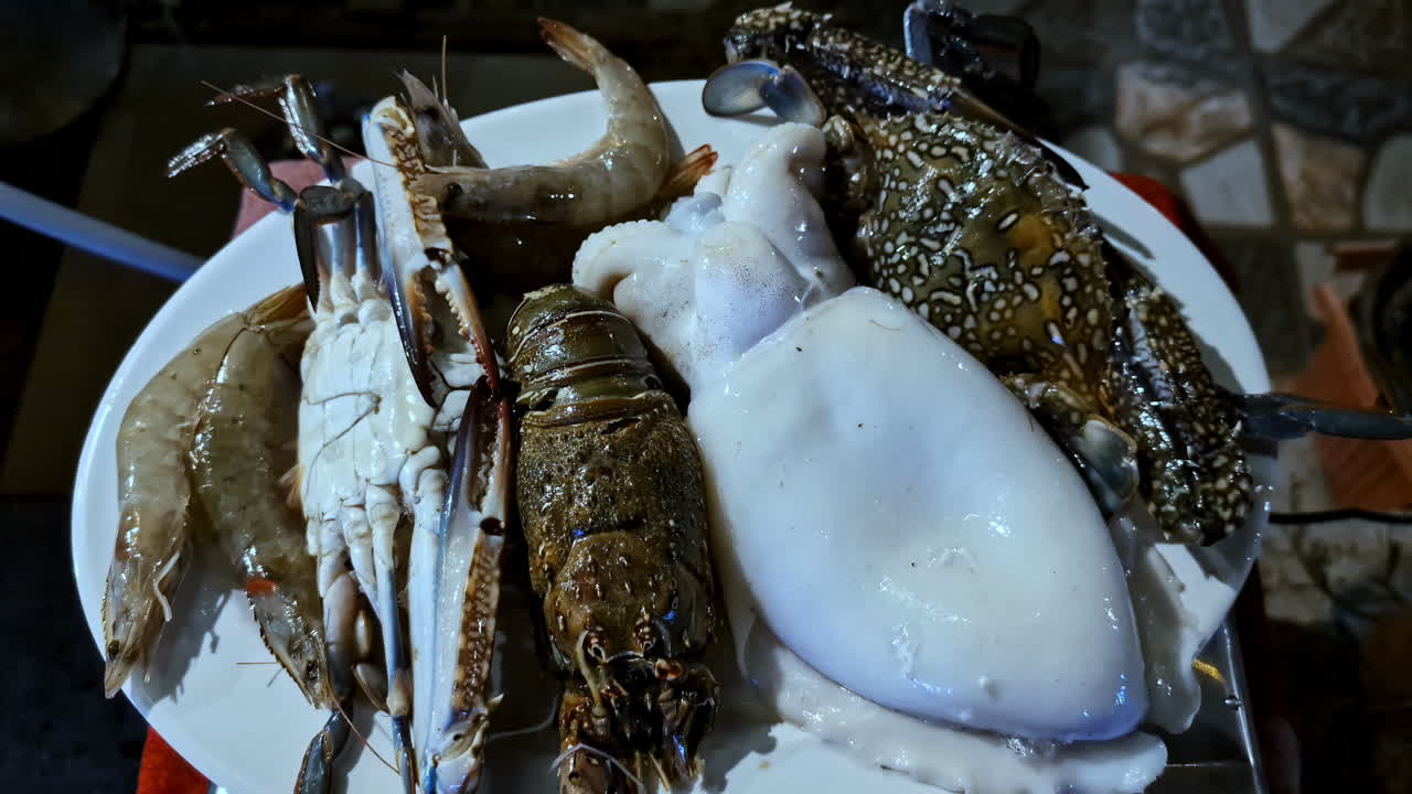 Assorted raw seafood including squid, crab, prawns, and lobster arranged on a white plate. Egypt