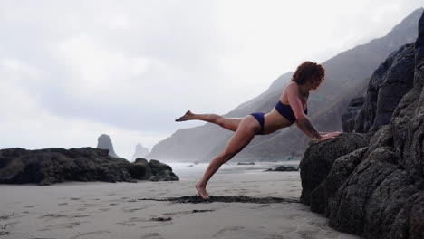 en cámara lenta, una joven y en forma mujer atleta realiza flexiones en una roca junto al océano