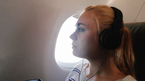 young woman enjoys the flight listening to music