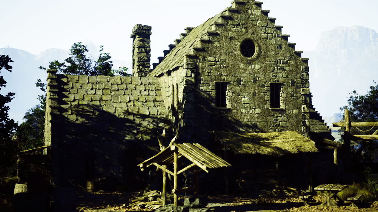 Old stone cottage surrounded by trees in a mountainous landscape