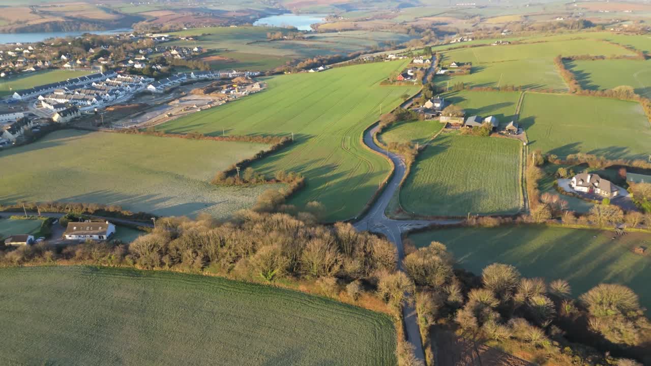 Drone over rural road and suburb of Kinsale with views over town in golden morning light