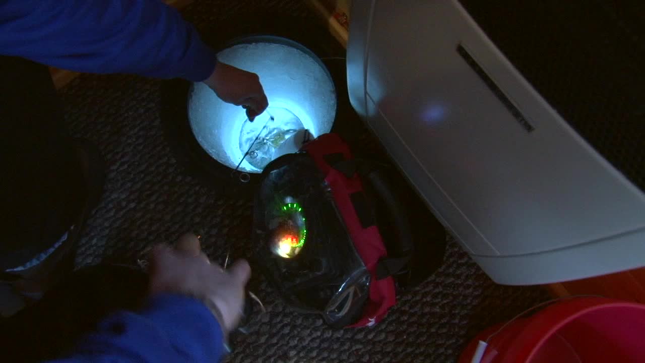 얼음 구멍을 만지작거리고 낚싯대로 물고기를 잡는 남자