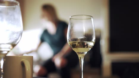 glass of white wine and girl enjoying house party in background