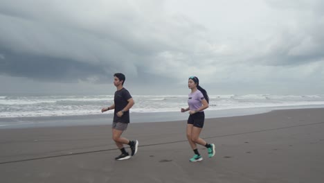 couple running on the beach on a cloudy day