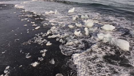 beach with ice floes washed by waves. diamond beach, jokulsarlon, iceland