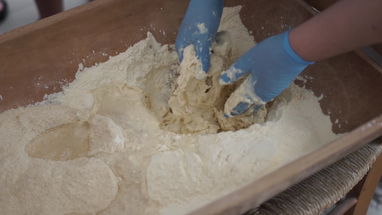 Top-down view of making bread the traditional way in a bakery by mixing and kneading by hand