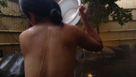 Female washing her back in traditional Japanese Onsen Outdoor Bath