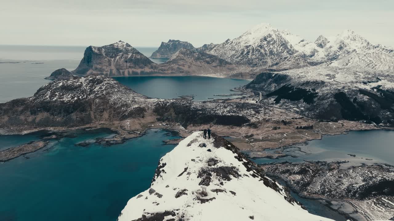 Snowy Mountain Range And Vagspollen Fjord From Offersoykammen Peak In Lofoten Islands, Norway. - aerial pullback shot