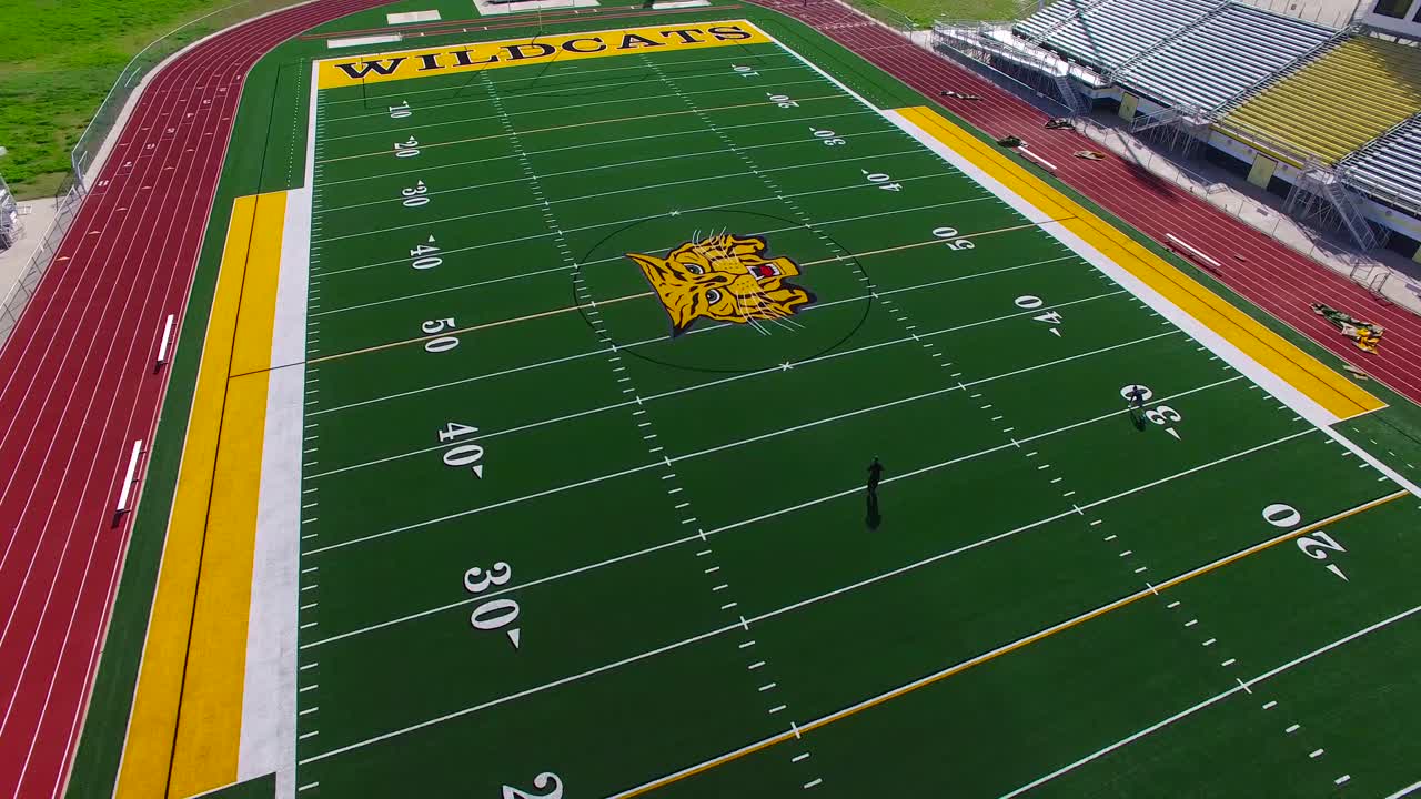 Vista aerea di un allenatore e di un giocatore che si allenano su un moderno campo da football americano di un liceo