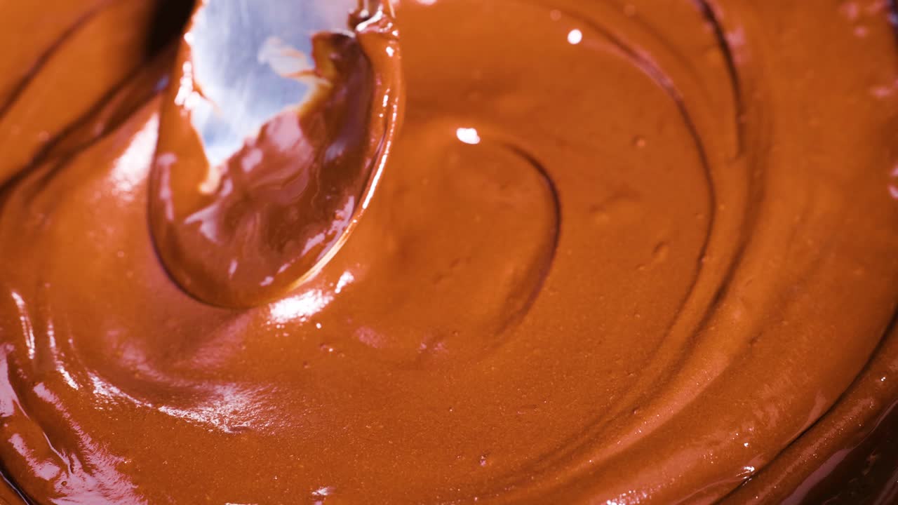 Cucchiaio che mescola cioccolato cremoso in una ciotola
