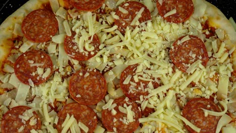 topdown aerial of an uncooked pepperoni pizza, with a tomato base and lots of grated cheese