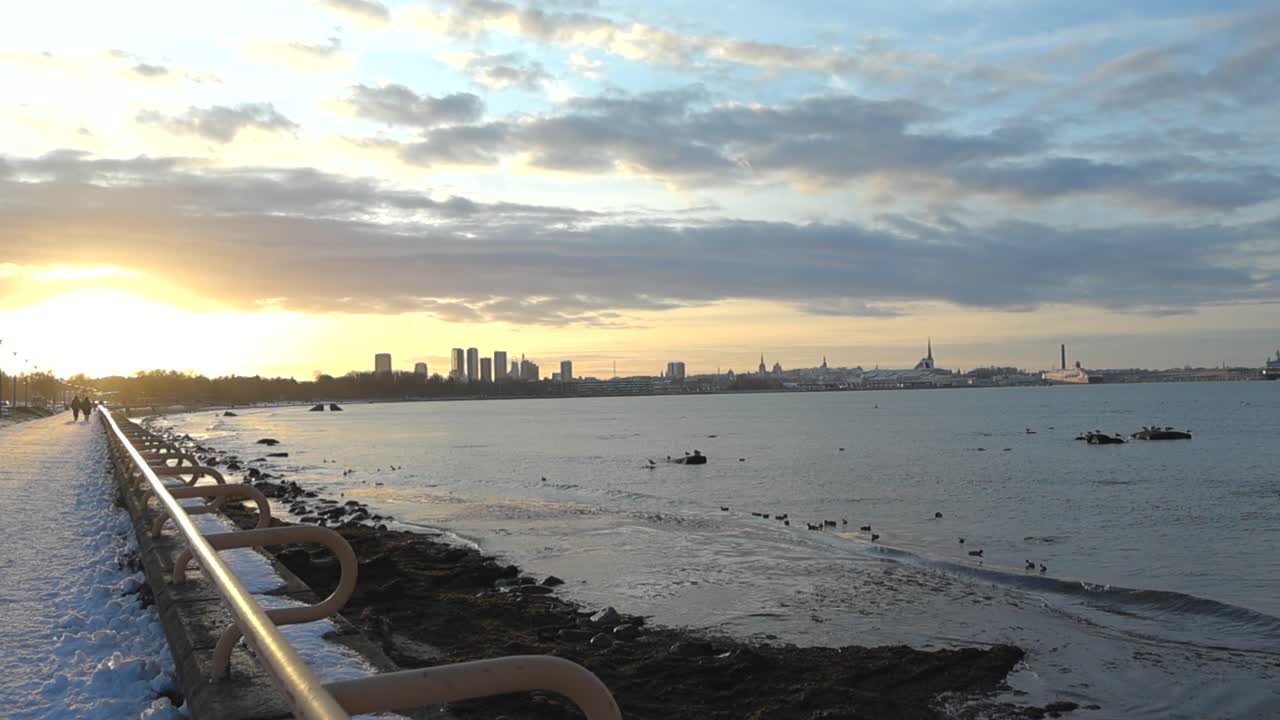 린 시의 화려한 오렌지 황금 노란색 해가 지거나 해가 뜨는 모습은 겨울 동안 발트해 해변에서 볼 수 있습니다. 바다의 물결이 서서히 오른쪽에 움직이고 있습니다. 해가 물에 반사됩니다.