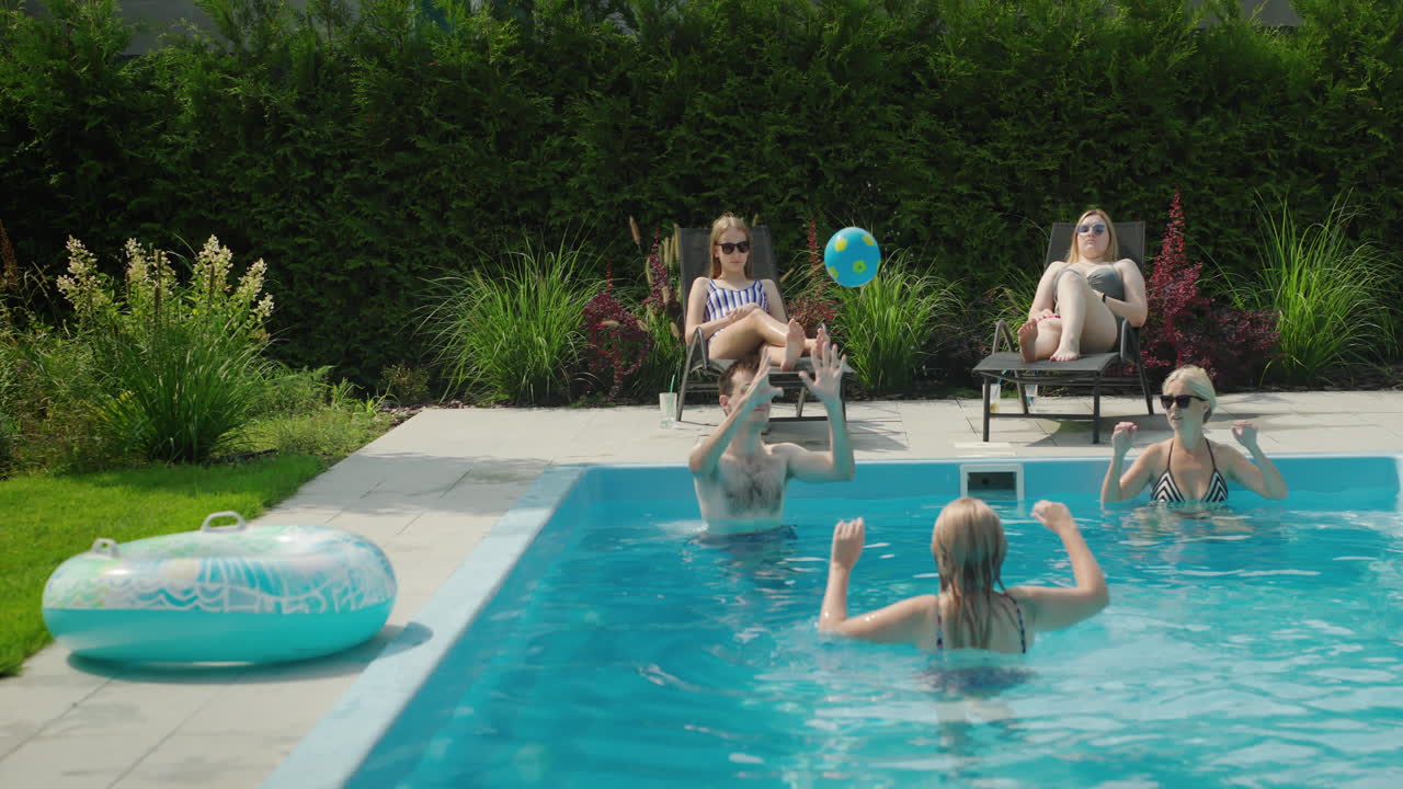 En hyggelig familie slapper af ved poolen og spiller bold. De hygger sig sammen på en varm sommerdag.