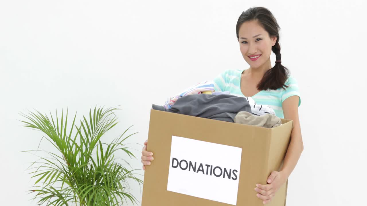 Pretty brunette holding donation box full of clothes