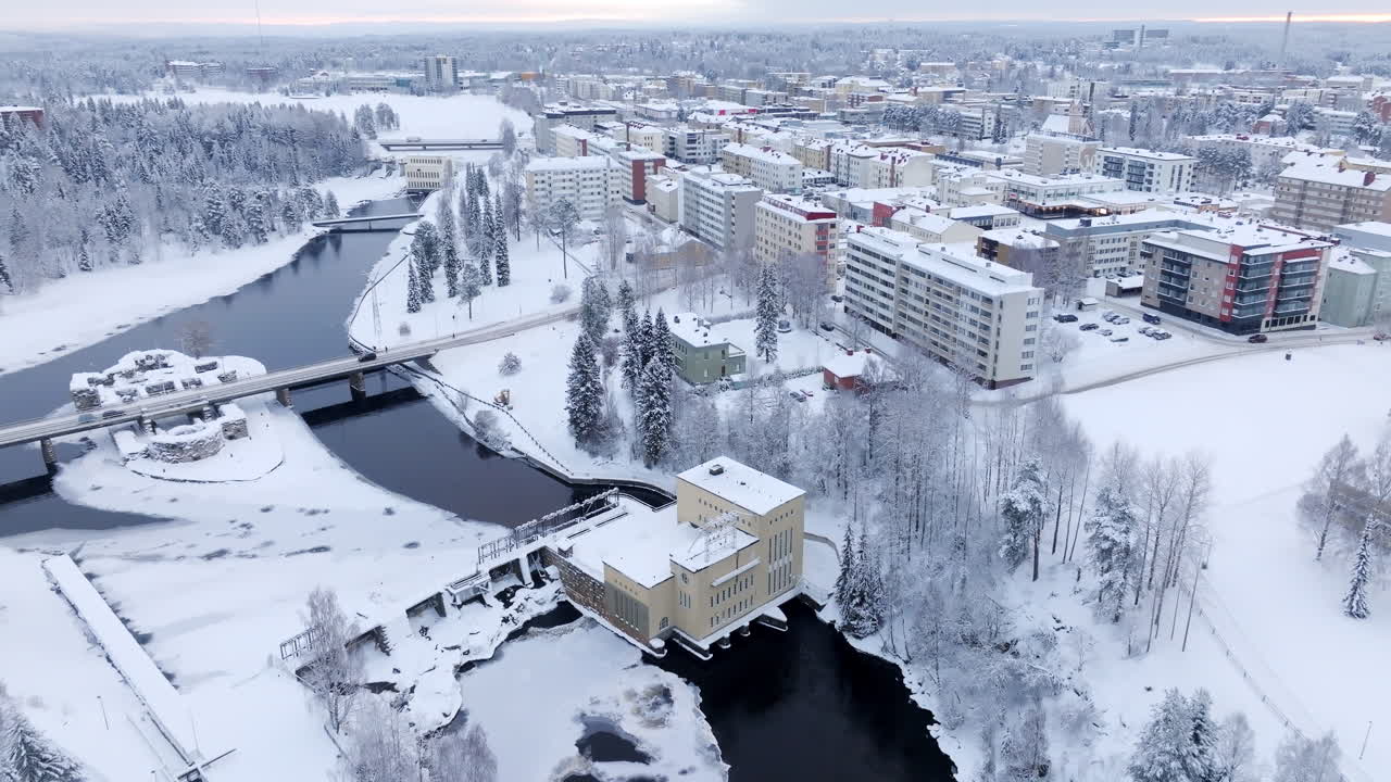 Drone rotating backwards over the Kajaani city, dam and castle, winter in Finland